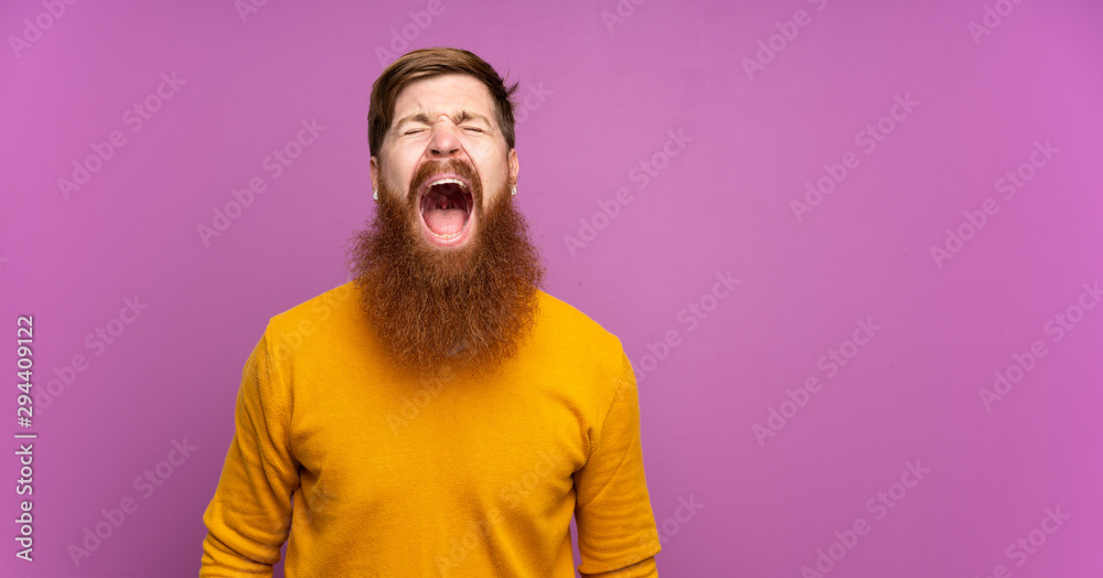 Redhead man with long beard over isolated purple background shouting to the front with mouth wide open