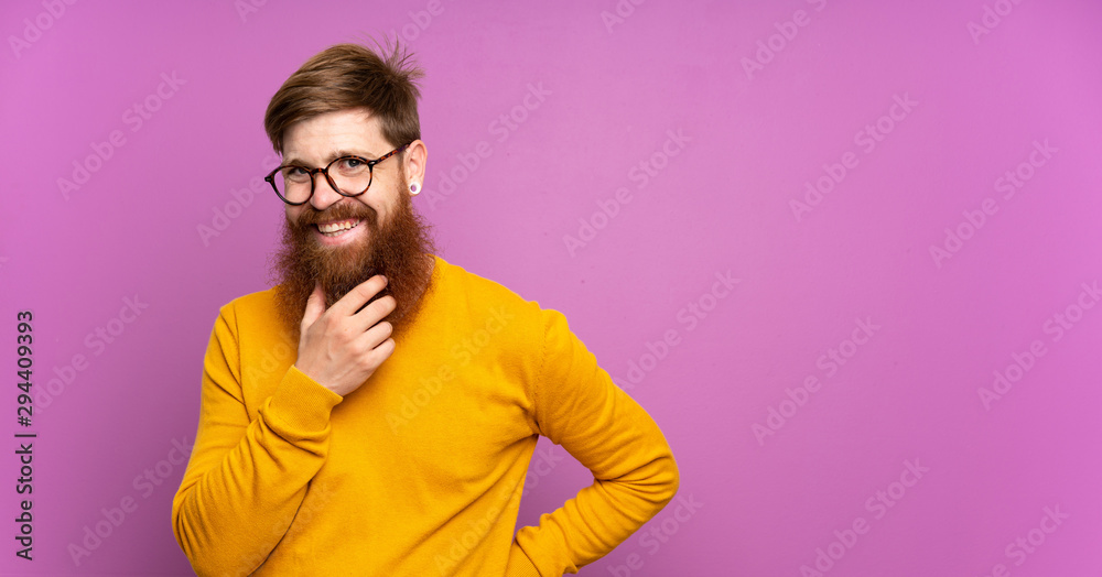 Redhead man with long beard over isolated purple background with glasses and smiling Redhead man with long beard over isolated purple background with glasses and smiling
