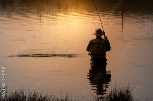 Back view of a fisherman catching a fish in the sunset