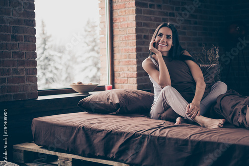 Portrait of her she nice-looking fresh healthy attractive charming cute pretty lovely cheerful cheery dreamy girl sitting in bed enjoying perfect weekend industrial brick loft modern style hotel room