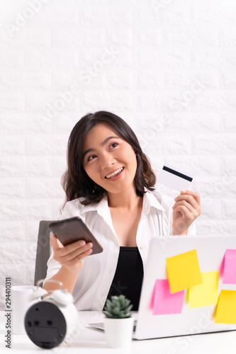 Happy woman use smart phone and credit card at office