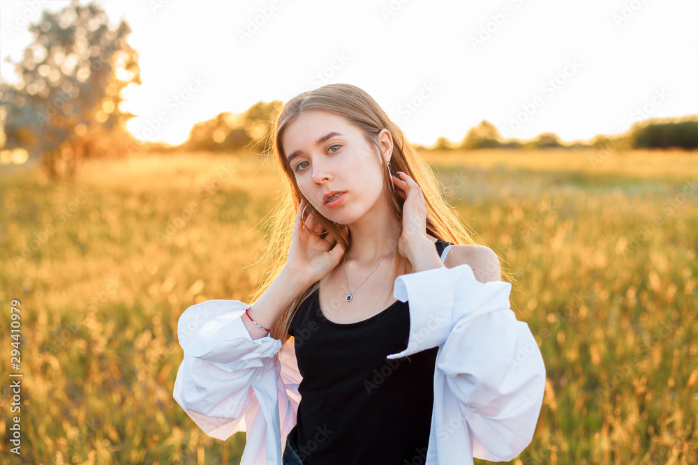 Beautiful young woman posing on the field at sunset Beautiful young woman posing on the field at sunset