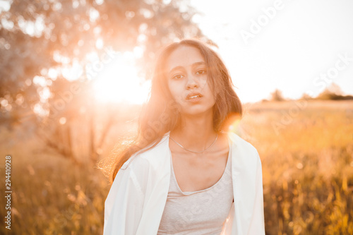 Portrait of young woman outdoors at sunset. Flare