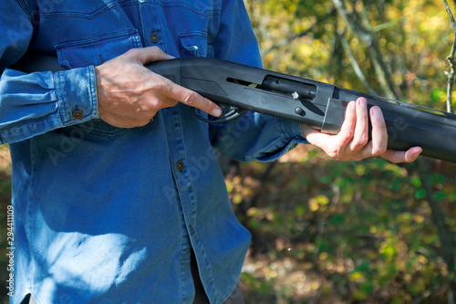 male with semi-automated shotgun in the autumn forest