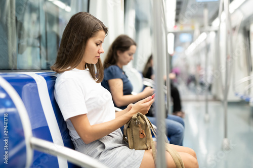 Woman sitting in subway car with phone