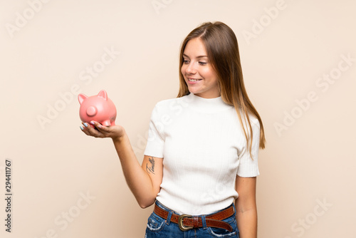 Young blonde woman over isolated background holding a big piggybank © luismolinero