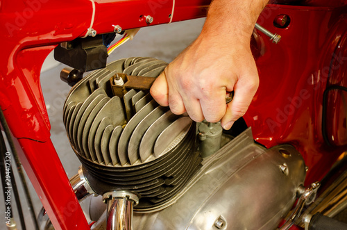 A man hand dismount spark plug from old motorbike engine