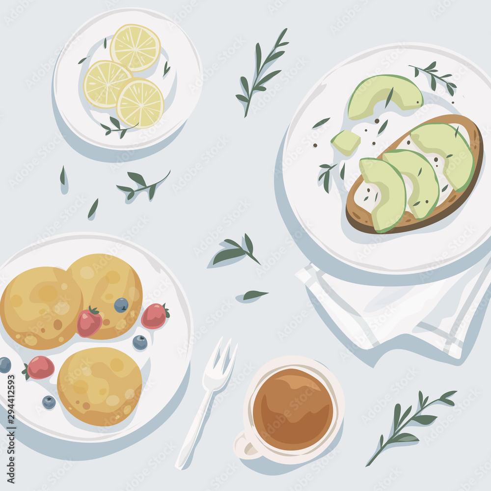 Breakfast top view. Cup of tea, lemon wedges, pancakes with fresh berries, toast with avocado