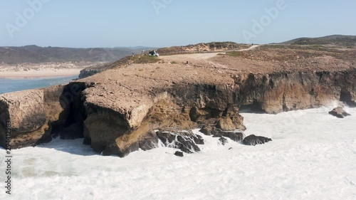 Ocean waves hitting the cliffs near Praia de Monte Clérigo in Portugal