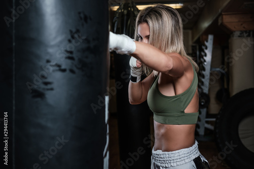 Beautiful boxer female has her training with punching bag at gym. © Fxquadro