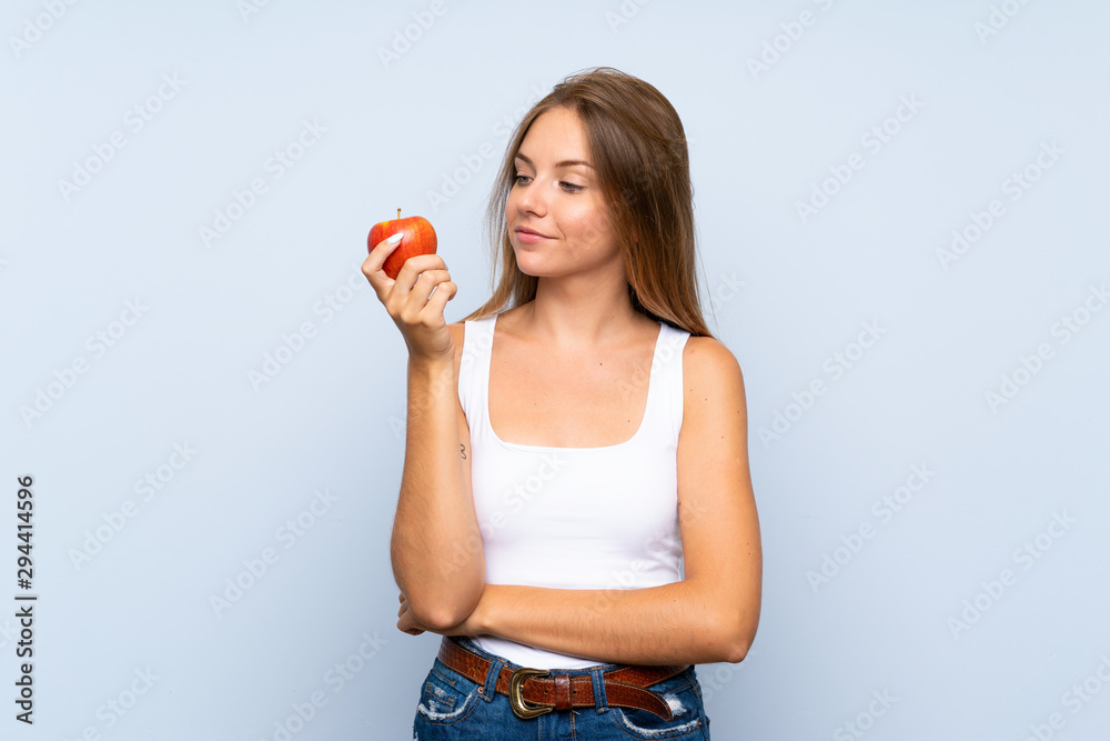 Young blonde girl with an apple over isolated background Young blonde girl with an apple over isolated background