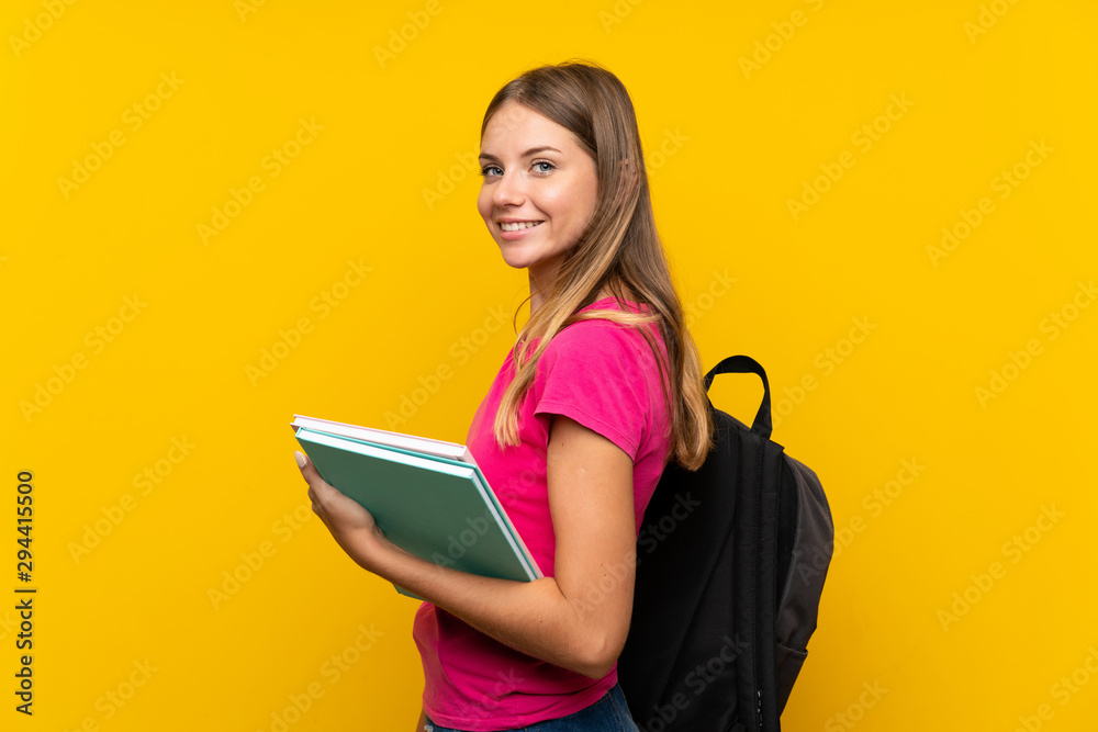 Young student girl over isolated yellow background smiling a lot Young student girl over isolated yellow background smiling a lot