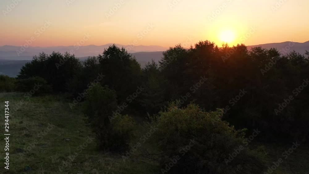 Drone video with couple watching a beautiful sunset on a mountain with their tent and mountain bikes aside. Adventure concept.