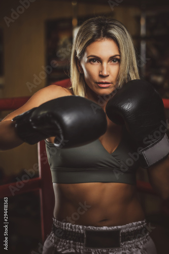 Focused muscular woman has her boxing training wearing boxing gloves.