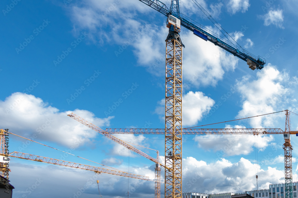background of construction site with cranes in sunny day with blue sky and white clouds background of construction site with cranes in sunny day with blue sky and white clouds