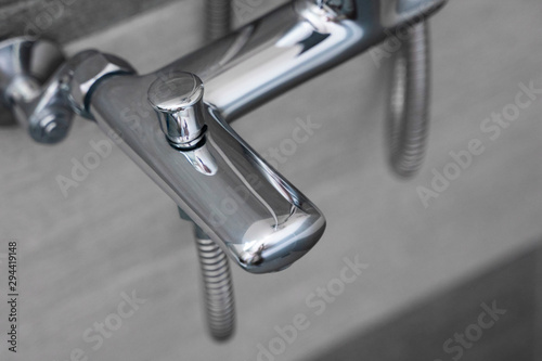 Modern designer tap and shower in bathroom. Closeup of chrome shower, faucet, in the bathroom covered decorative ceramic. Mixer cold hot water.