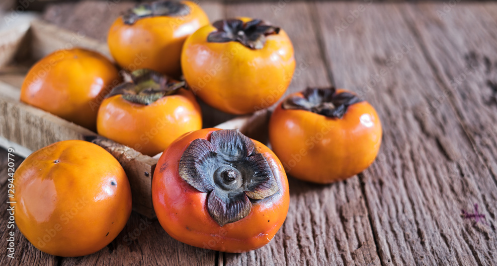 Whole ripe persimmon on a wooden old background. Whole ripe persimmon on a wooden old background.
