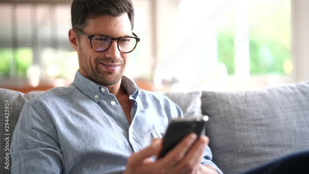 Smiling man relaxing in sofa, talking on phone