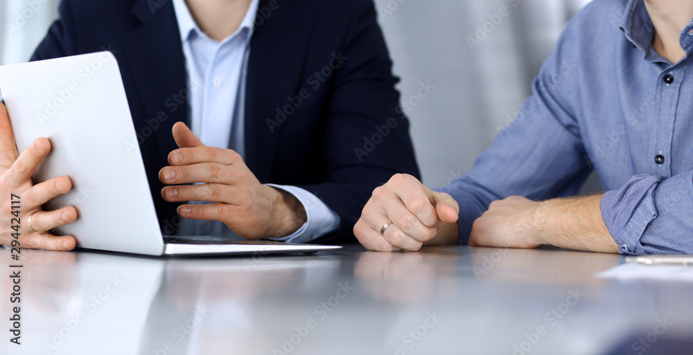 Business people using laptop computer while working together at the desk in modern office. Unknown businessman or male entrepreneur with colleague at workplace. Teamwork and partnership concept Business people using laptop computer while working together at the desk in modern office. Unknown businessman or male entrepreneur with colleague at workplace. Teamwork and partnership concept