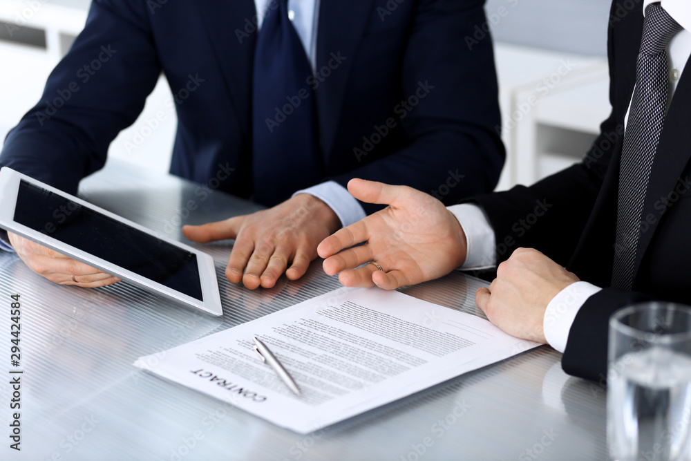 Business people using tablet computer while working together at the desk in modern office. Unknown businessman or male entrepreneur with colleague at workplace. Teamwork and partnership concept Business people using tablet computer while working together at the desk in modern office. Unknown businessman or male entrepreneur with colleague at workplace. Teamwork and partnership concept