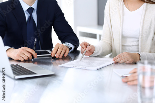 Business people discussing contract working together at meeting at the glass desk in modern office. Unknown businessman and woman with colleagues or lawyers at negotiation. Teamwork and partnership