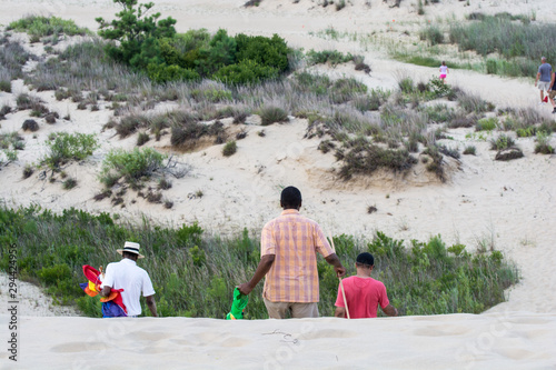 Family walking down sand dune at beach on family vacation at the Outer Banks in North Carolina. © Jessica