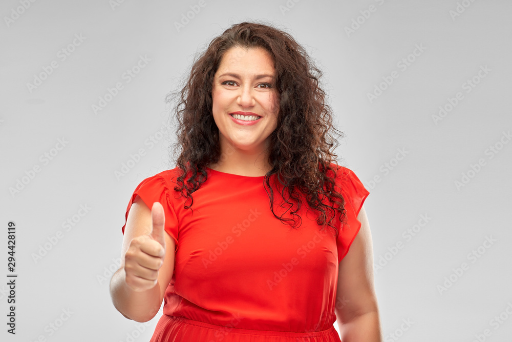 people and gesture concept - happy woman in red dress showing thumbs up over grey background people and gesture concept - happy woman in red dress showing thumbs up over grey background