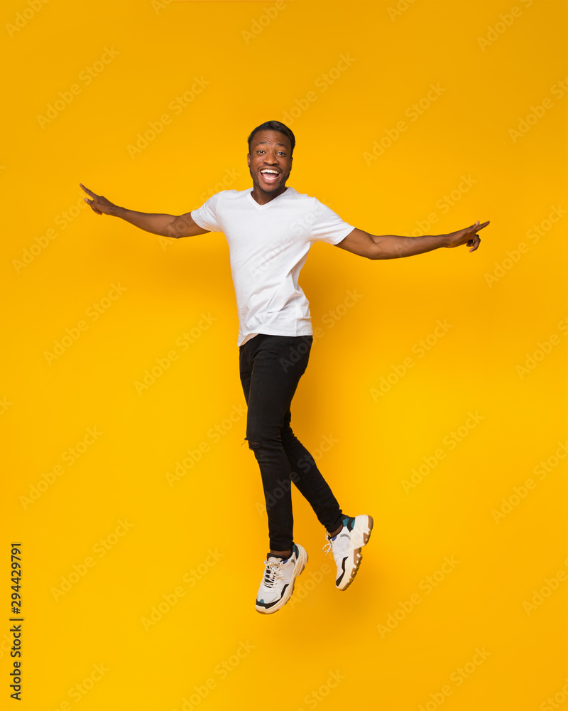 African American Guy Jumping Having Fun Over Yellow Background