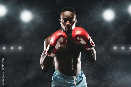 Confident black boxer standing in pose, ready to fight photo