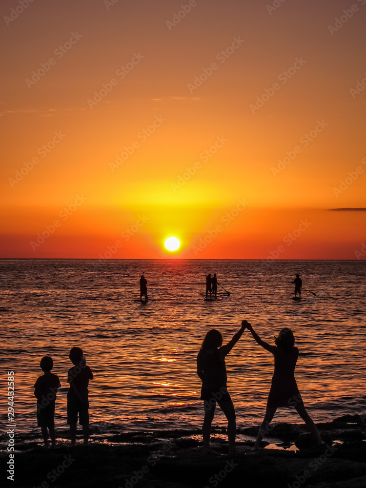 Happy people watching a sunset on the beach Happy people watching a sunset on the beach