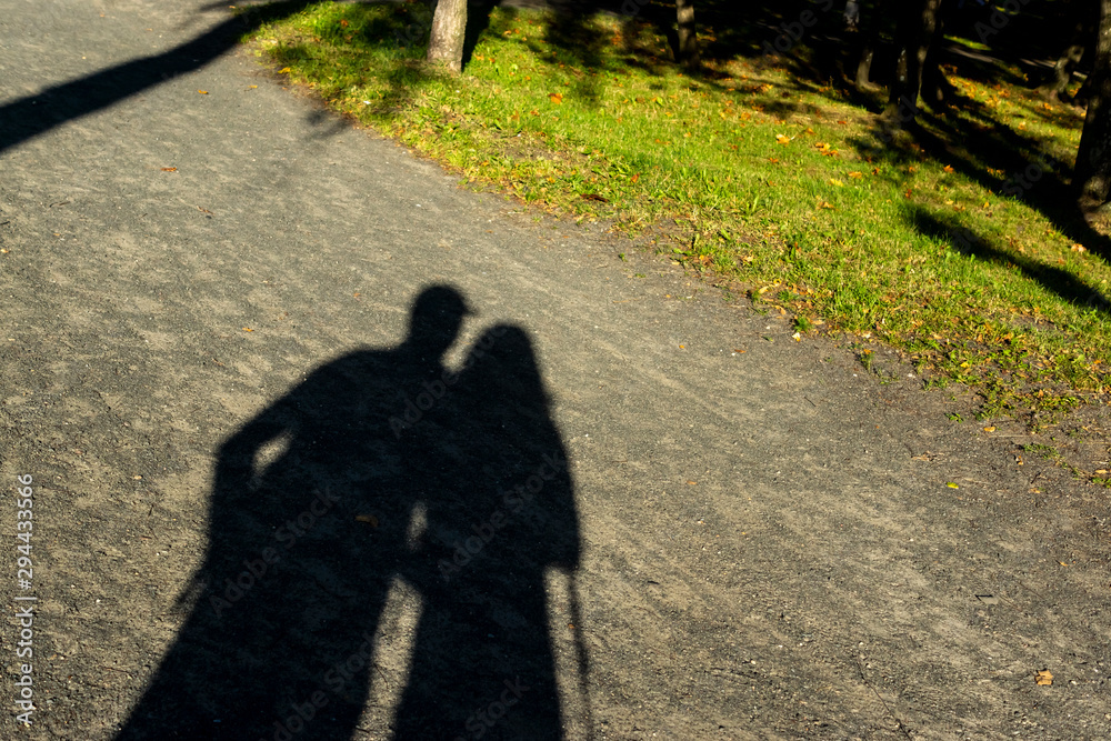 Shadows of man and woman fall on summer park path bathed in evening sun  Stock Photo | Adobe Stock
