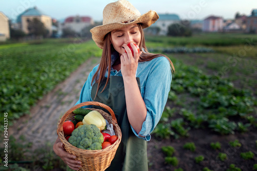 Pretty gardener girl enjoying the smell of fresh vegetables she has in a basket