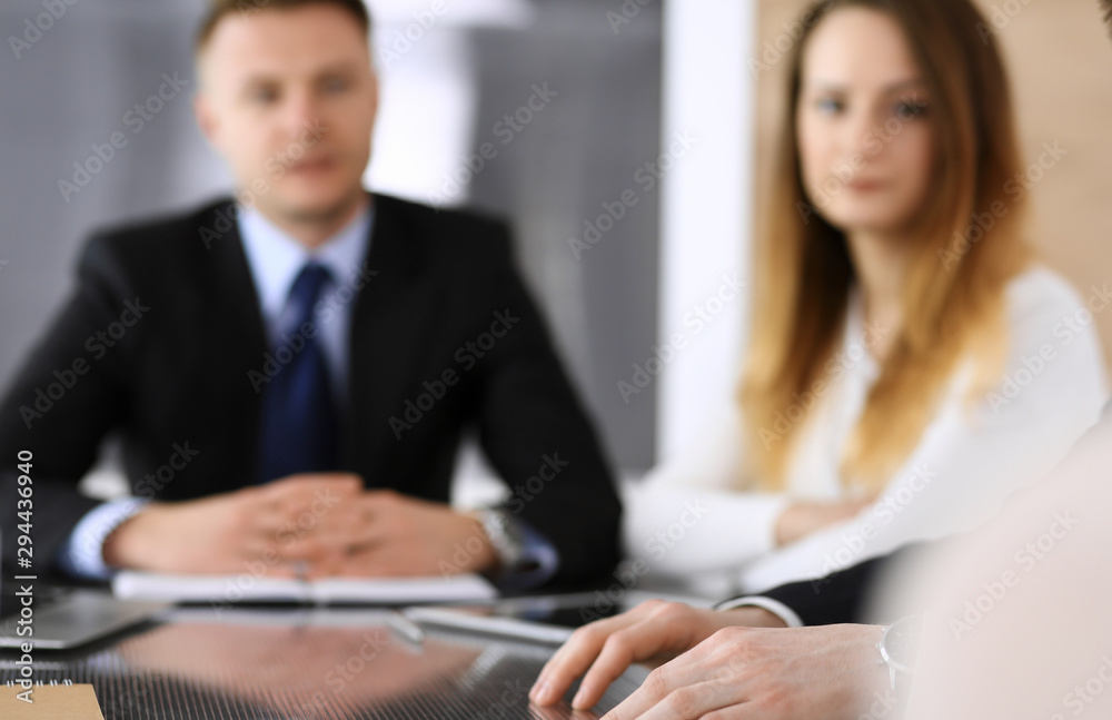 Obraz premium Business people or lawyers discussing questions of contract at meeting in modern office, close-up. Unknown businessman and woman with colleague sitting and working at the glass desk. Teamwork and