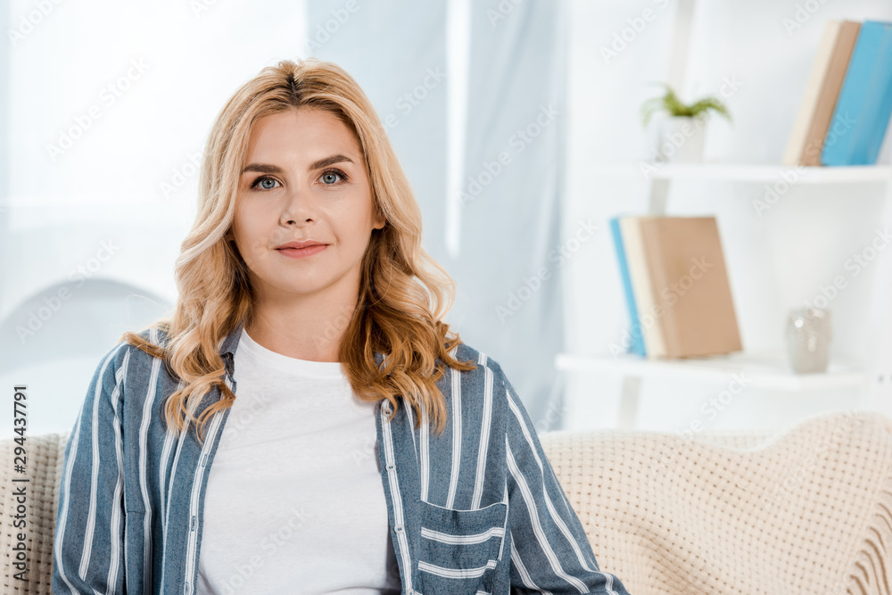 Naklejka premium attractive woman looking at camera in living room