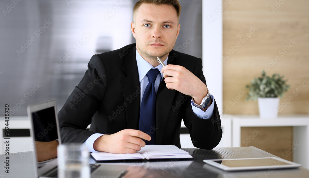 Businessman headshot at meeting in modern office. Unknown entrepreneur sitting with colleagues at the background. Teamwork and partnership concept Businessman headshot at meeting in modern office. Unknown entrepreneur sitting with colleagues at the background. Teamwork and partnership concept