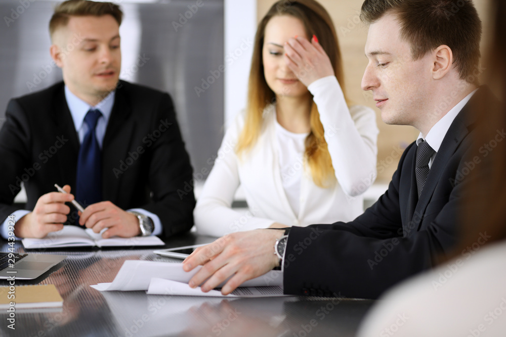 Business people or lawyers discussing questions at meeting in modern office. Unknown businessman and woman with colleague sitting and working at the glass desk. Teamwork and partnership concept Business people or lawyers discussing questions at meeting in modern office. Unknown businessman and woman with colleague sitting and working at the glass desk. Teamwork and partnership concept