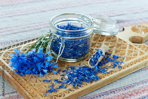 Blue cornflower or centaurea flower tea is good as diuretic, in cosmetics and eyewash, fresh blossom and a jar with dry petals nearby, closeup, copy space, herbal drinks concept photo