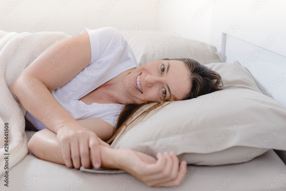 Beautiful woman smiling while waking up in her bed. Beautiful woman smiling while waking up in her bed.