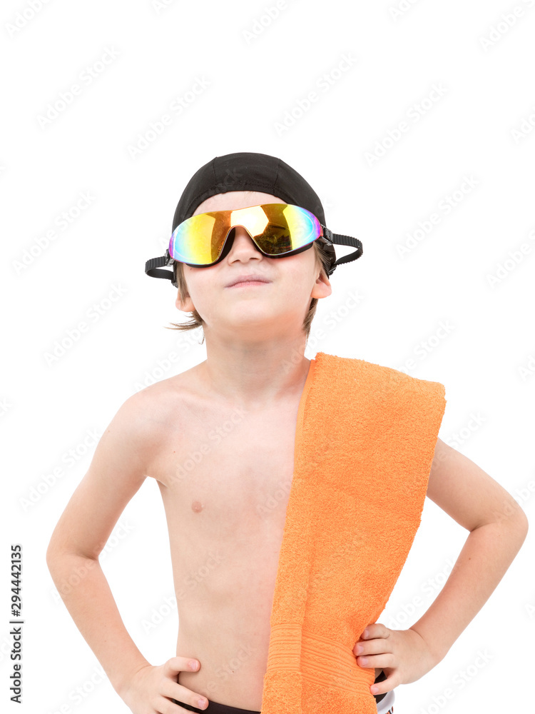 Smart kid in swimming shorts and black hat and goggles on head with orange towel on neck