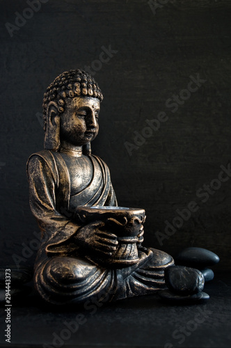 Bronze Gautama Buddha with Dark Rocks Isolated on Black