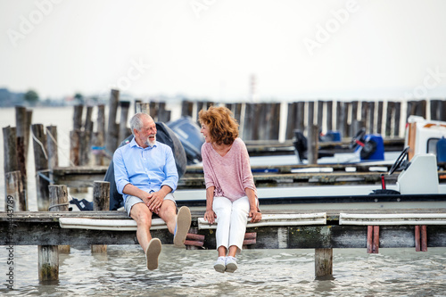 Senior couple on a holiday sitting by the lake, talking. © Halfpoint