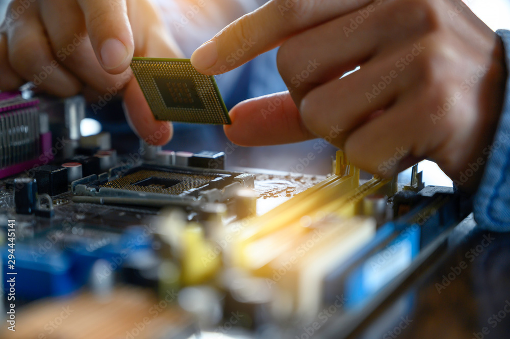 The asian technician is putting the CPU on the socket of the computer motherboard. the concept of computer hardware, repairing, upgrade and technology.