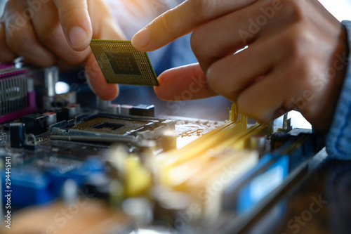 The asian technician is putting the CPU on the socket of the computer motherboard. the concept of computer hardware, repairing, upgrade and technology.