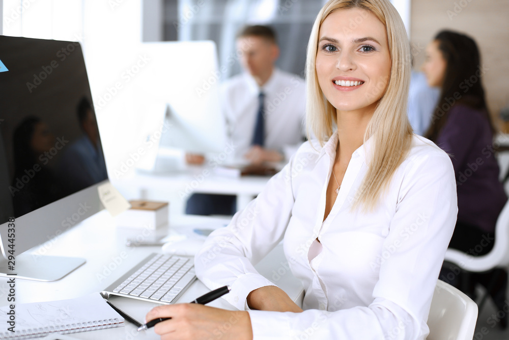 Business woman using computer at workplace in modern office. Secretary or female lawyer smiling and looks happy. Working for pleasure and success