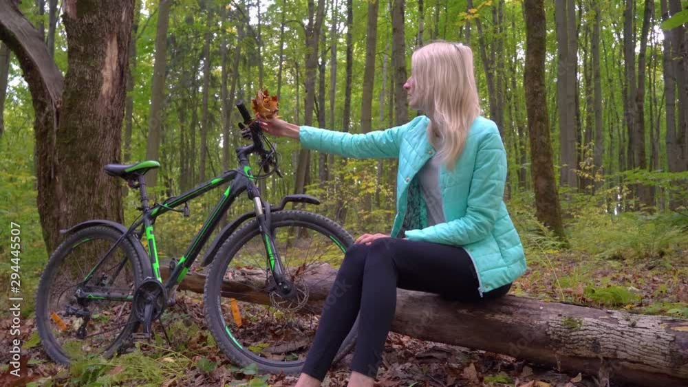 woman sits in park on background of bicycle, Autumn, bouquet of leaves. woman sits in park on background of bicycle, Autumn, bouquet of leaves.