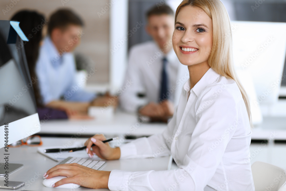Business woman using computer at workplace in modern office. Secretary or female lawyer smiling and looks happy. Working for pleasure and success Business woman using computer at workplace in modern office. Secretary or female lawyer smiling and looks happy. Working for pleasure and success