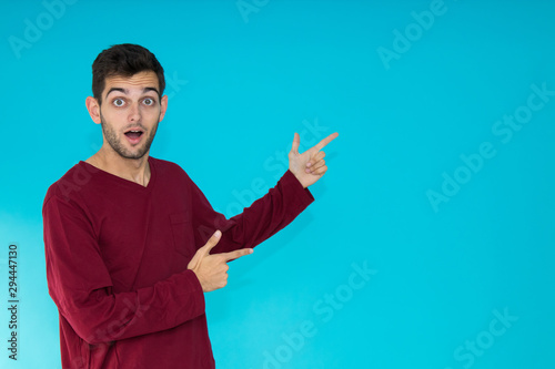 isolated young man pointing at color background