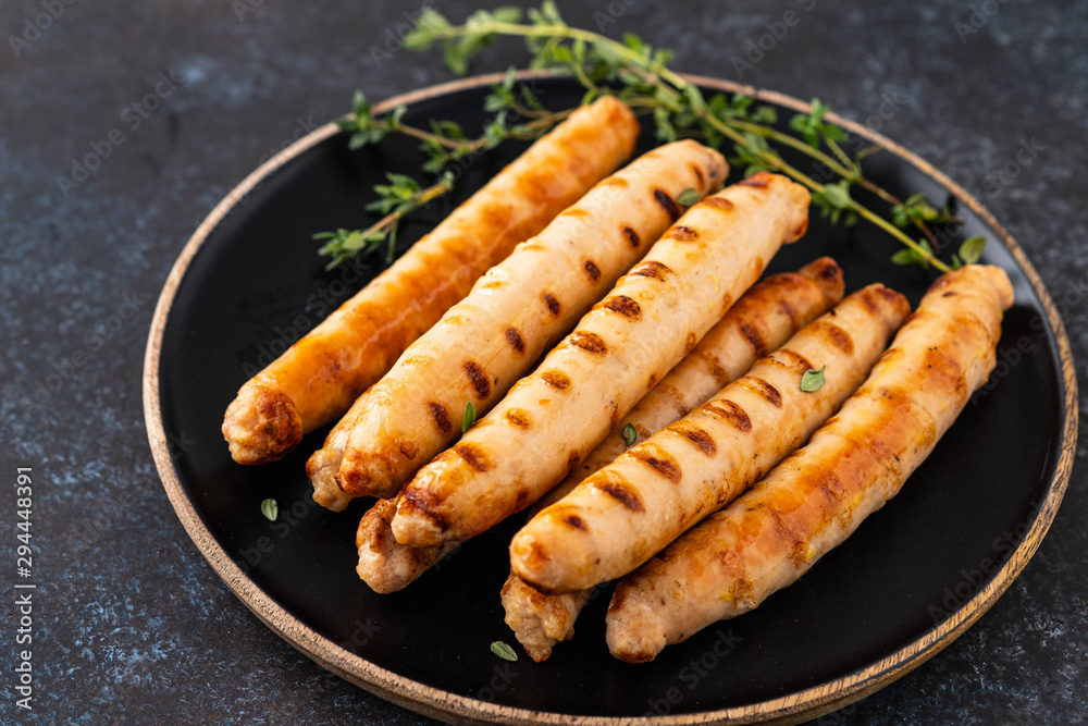 Grilled sausages on black plate with tomato sauce and thyme. Copy space. Grilled sausages on black plate with tomato sauce and thyme. Copy space.