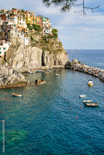 Obraz na płótnie Manarola, Cinque Terre, Italy - August 17, 2019: Picturesque village in the province of La Spezia. Colorful houses on the coastal cliffs. Ligurian Sea Bay with moored boats w salonie