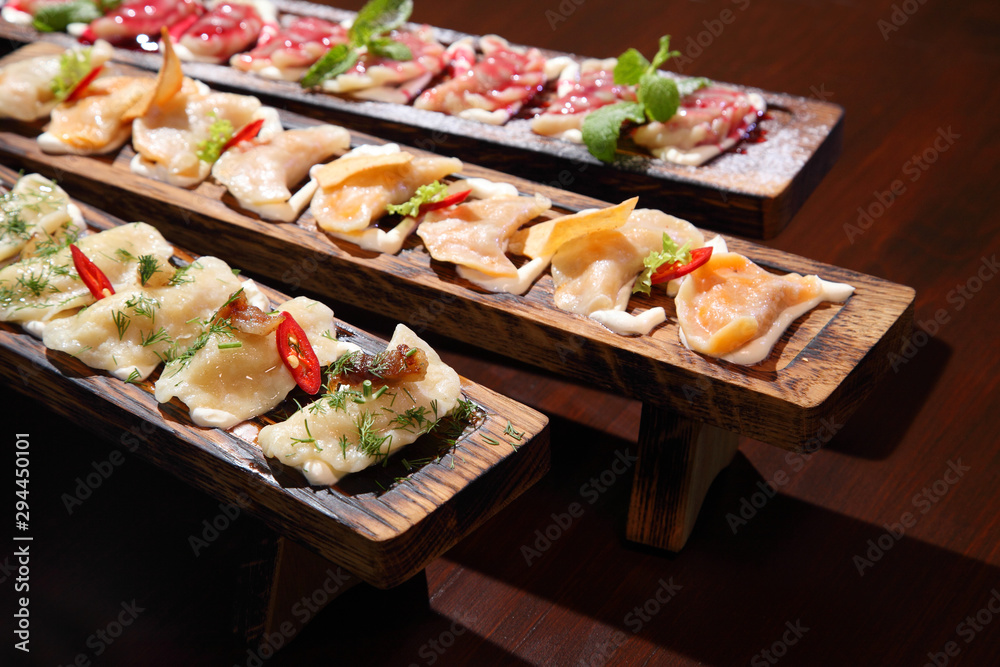 Dumplings with potato in sour cream on a wooden board.  Dumplings with mushrooms. Dumplings with cherries.